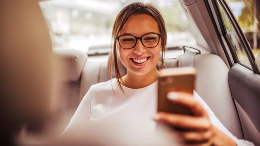 Junge Frau im Taxi mit Smartphone